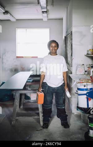 Portrait complet d'une femme peintre souriante debout dans un atelier Banque D'Images