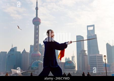 Pratiquer le Tai Chi avec l'épée, avec l'horizon de Pudong, tôt le matin, Shanghai, Chine Banque D'Images