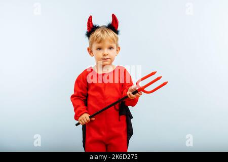 Mignon petit garçon en costume d'halloween diable avec cornes et trident Banque D'Images