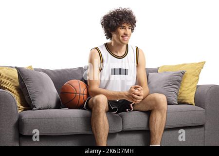 Joueur de basket-ball assis sur un canapé et souriant isolé sur fond blanc Banque D'Images