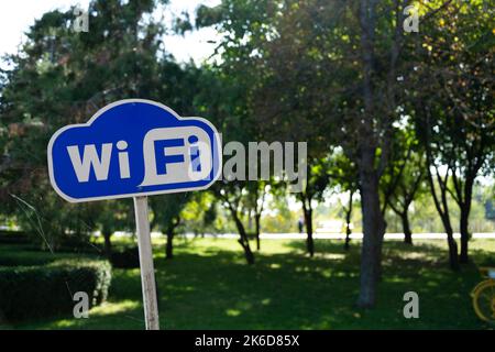 Signe Wi-Fi. Panneau WiFi bleu et blanc sur fond vert dans le parc Banque D'Images