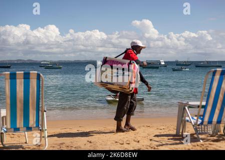 Salvador, Bahia, Brésil - 04 juin 2022: Les vendeurs de rue marchent sur le sable de la plage de Porto da Barra à Salvador, Bahia. Banque D'Images