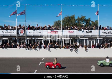 Les enfants s'affrontent dans leurs voitures à pédales Austin J40 sur la ligne droite dans la course Settrington Cup, Revival Meeting, circuit automobile de Goodwood, Goodwood, Royaume-Uni Banque D'Images