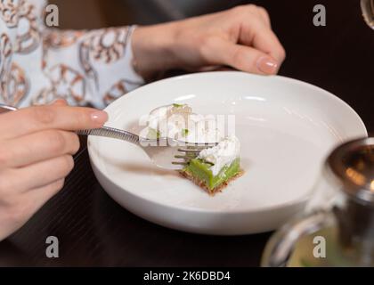 Vue rognée d'une femme en train de couper un dessert sain avec une fourchette Banque D'Images