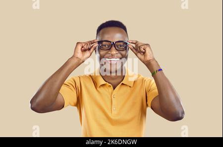 Studio portrait d'un jeune Africain heureux mettant sur ses lunettes et souriant Banque D'Images