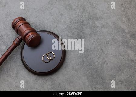 Thème droit. Jugez les anneaux de mariage de gavel sur fond gris en pierre de béton. Procédure de divorce. Maillet de juge qui décide du divorce de mariage, de l'accord matrimonial, des légalités du divorce Banque D'Images