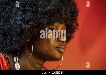 Femme africaine face à l'intérieur avec la lumière orange et les cheveux traditionnels africains Banque D'Images