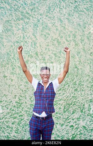 un jeune homme afro-américain lève les bras en mode victoire ou célébration en regardant la caméra Banque D'Images