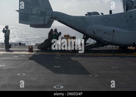 221013-N-XN177-2012 MER DES PHILIPPINES (OCT 13, 2022) – les Marines des États-Unis chargent de l'équipement sur un avion Tiltrotor MV-22 Osprey affecté à l'escadron Tiltrotor moyen marin (VMM) 262 (renforcé) sur le pont de vol à bord du porte-avions amphibie USS Tripoli (LHA 7) le 13 octobre 2022. Tripoli opère dans la zone d'opérations de la flotte américaine 7th afin d'améliorer l'interopérabilité avec ses alliés et ses partenaires et de servir de force de réaction prête à l'emploi pour défendre la paix et maintenir la stabilité dans la région Indo-Pacifique. (É.-U. Photo de la marine par le spécialiste des communications de masse 1st classe Peter Burghart) Banque D'Images