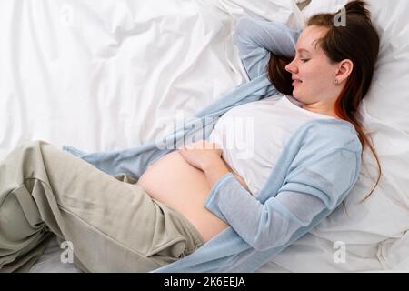 Vue de dessus enceinte femme enceinte caressant son ventre. Femme mains touchant son ventre, enfant en attente, couché sur le lit préparation à l'accouchement, fille Banque D'Images