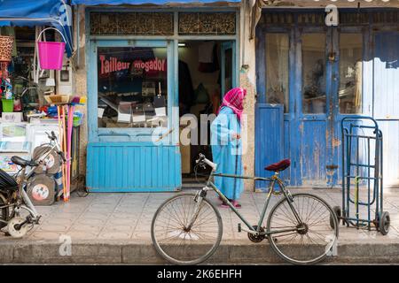 Femme dans les vêtements traditionnels marocains marche dans les magasins de la vieille ville historique d'Essaouira, Maroc, Afrique du Nord Banque D'Images