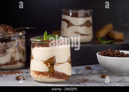 Pots avec gâteau de tiramisu superposé sur fond rustique foncé Banque D'Images