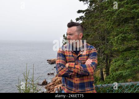 Parc national Acadia, Maine, États-Unis. Touriste au-dessus de la côte rocheuse à Bass Harbor Head et au phare de Bass Harbor Head. Banque D'Images