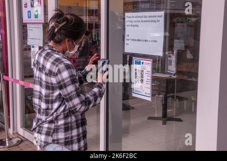 Une femme cambodgienne, dans un masque facial protecteur, scanne son code QR à l'entrée de Eon Mall 1. Phnom Penh, Cambodge. 9th octobre 2021. © Kraig Lieb Banque D'Images
