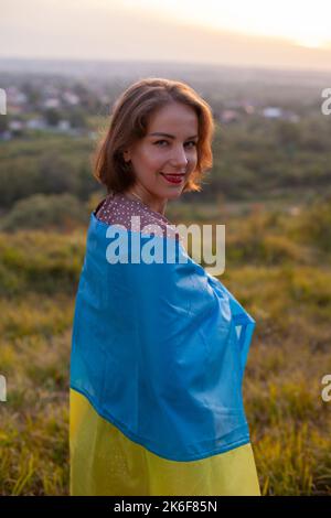 Femme heureuse en robe longue portant un drapeau jaune et bleu de l'Ukraine Banque D'Images