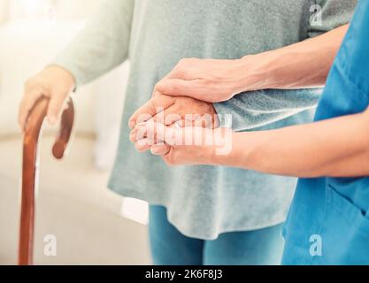 La gentillesse inattendue est la plus puissante. une femme âgée utilisant une canne à pied avec l'aide de son infirmière. Banque D'Images