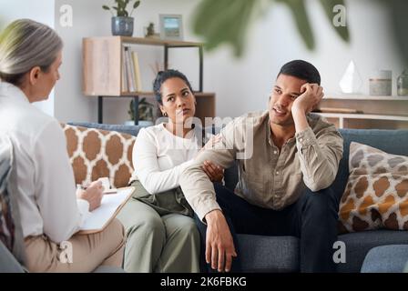 C'est tellement frustrant. un jeune couple assis ensemble et regardant concerné lors d'une consultation avec un psychologue. Banque D'Images