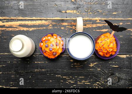 Délicieux petits gâteaux d'Halloween, bouteille et tasse de lait sur fond de bois Banque D'Images