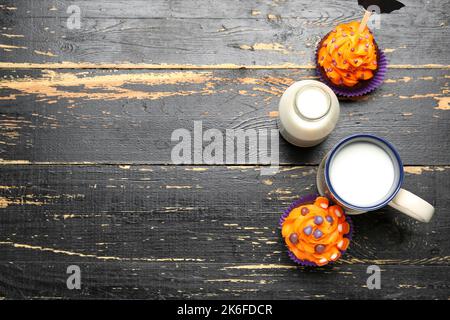 Délicieux petits gâteaux d'Halloween, bouteille et tasse de lait sur fond de bois Banque D'Images