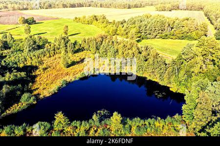 Étang bleu profond dans une lande verte en face des champs et des prairies, vue aérienne Banque D'Images