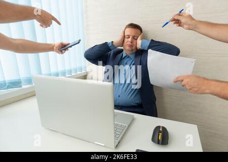 Un homme en costume bleu avec une tête douloureuse dans le bureau. Le concept de surmenage au travail. Un homme d'affaires fatigué tient la tête avec ses mains. Le patron est t Banque D'Images