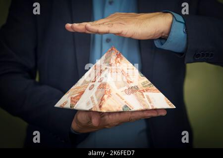 un schéma pyramidal entre les mains d'un fraudeur.Le concept d'échange sur les marchés financiers est l'effondrement du système financier du capitalisme. Banque D'Images