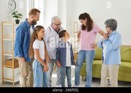 Mère heureuse avec le reste de la famille debout dans la salle de séjour et parlant aux enfants Banque D'Images