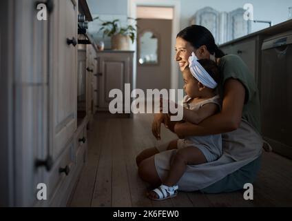 Lorsque vous apprenez à cuisiner, rien ne dit de patience comme regarder un gâteau. Une mère mignonne et sa petite fille curieuse regardant un four. Enfant et Banque D'Images