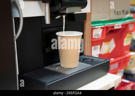 prépare l'espresso. la machine à café verse du café chaud dans une tasse en carton. Banque D'Images