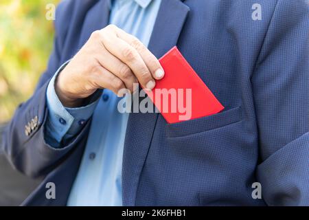 Un homme d'affaires en costume noir montre sa carte d'identité.Un fonctionnaire ayant un statut élevé affiche son document rouge.Immunité parlementaire, carte d'identité vierge pour tes Banque D'Images