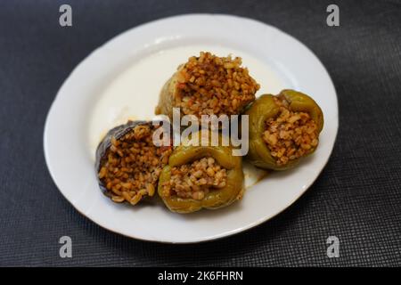 Poivrons farcis, aubergines et courgettes avec yaourt sur une plaque blanche sur fond noir texturé, dolma avec yaourt cuisine traditionnelle turque Banque D'Images