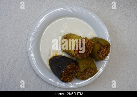 Poivrons farcis, aubergines et courgettes avec yaourt sur une plaque blanche sur fond noir texturé, dolma avec yaourt cuisine traditionnelle turque Banque D'Images