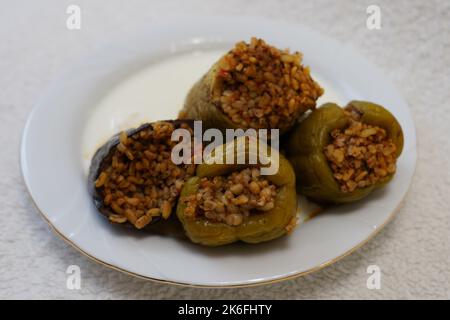 Poivrons farcis, aubergines et courgettes avec yaourt sur une plaque blanche sur fond noir texturé, dolma avec yaourt cuisine traditionnelle turque Banque D'Images