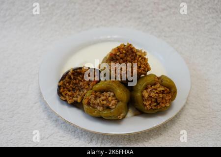 Poivrons farcis, aubergines et courgettes avec yaourt sur une plaque blanche sur fond noir texturé, dolma avec yaourt cuisine traditionnelle turque Banque D'Images