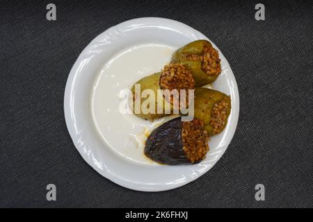 Poivrons farcis, aubergines et courgettes avec yaourt sur une plaque blanche sur fond noir texturé, dolma avec yaourt cuisine traditionnelle turque Banque D'Images