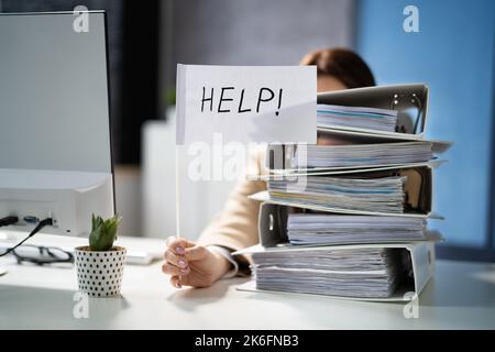 Sad Men in Office with Tax Workload and Paper Files Holding Help Flag Banque D'Images