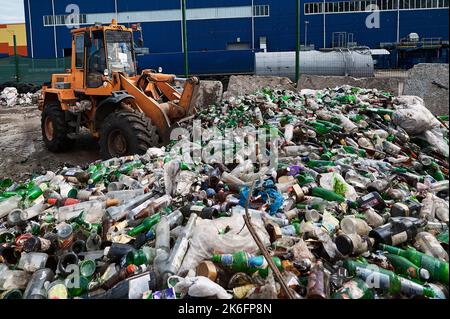 Le chargeur de godet brise les bouteilles en verre en les déchargeant du godet. Préparation des récipients en verre pour le recyclage Banque D'Images