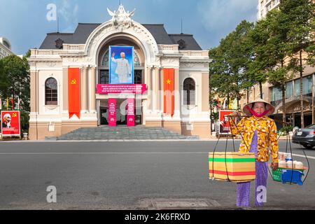 Un motard vietnamien portant un chapeau de bambou vendant de la nourriture en face de l'Opéra, Ho Chi Minh ville, Vietnam Banque D'Images