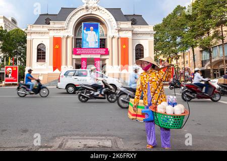 Un motard vietnamien portant un chapeau de bambou vendant de la nourriture en face de l'Opéra, Ho Chi Minh ville, Vietnam Banque D'Images