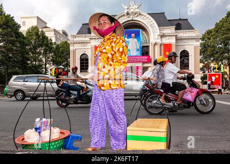 Un motard vietnamien portant un chapeau de bambou vendant de la nourriture en face de l'Opéra, Ho Chi Minh ville, Vietnam Banque D'Images