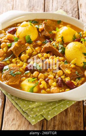 Cholent ou hamin est un ragoût juif traditionnel composé de viande, de pommes de terre, de haricots et d'orge dans la casserole sur la table. Verticale Banque D'Images