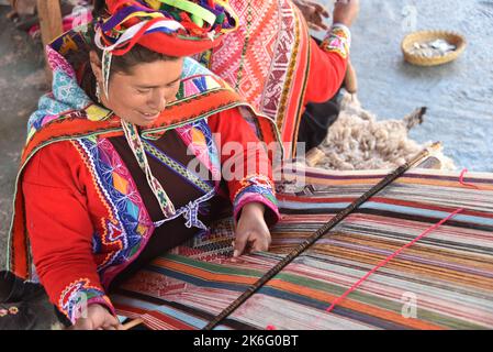 Cusco, Pérou - 1 juillet 2022 : une dame quechua tisse des textiles andins traditionnels à l'aide de laine d'alpaga Banque D'Images