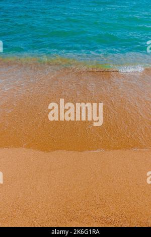 Photo verticale de l'eau bleu cristal de l'océan et de petites vagues sur la plage de sable, Espagne Banque D'Images