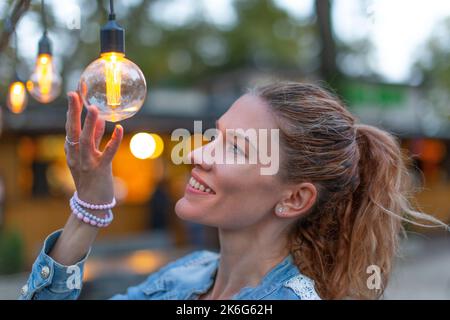Jeune femme caucasienne tenant une ampoule à LED à faible consommation d'énergie à l'extérieur Banque D'Images