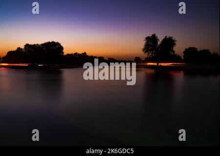 Vue sur le lac Love au coucher du soleil dans le désert d'Al Qudra, silhouettes d'arbres, fond ciel violet et bleu Banque D'Images