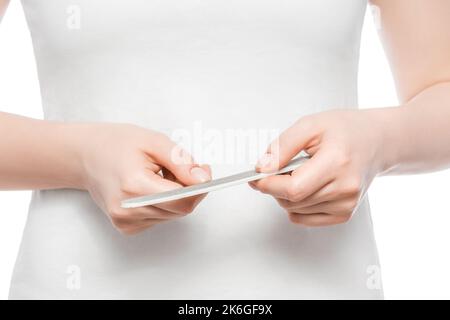 Coupe courte d'une femme dans un t-shirt blanc qui lui dépose ses ongles. Gros plan, isolé. Banque D'Images