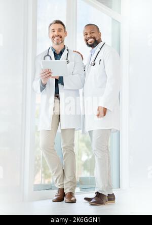 Ensemble comme le top dans leur domaine. deux médecins matures utilisant une tablette dans un bureau. Banque D'Images