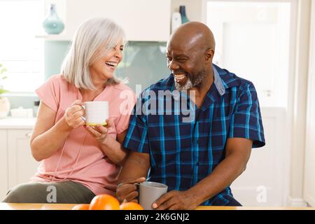 Heureux senior divers couple de boire du café dans la cuisine Banque D'Images