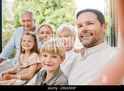 Une famille de plusieurs générations qui rassemble les selfies. Homme d'âge moyen assis avec sa famille et prenant des photos. Bonne adhésion de famille à la maison Banque D'Images