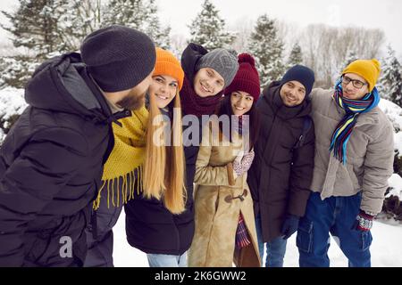 Les jeunes souriants se détendent à pied dans un parc enneigé Banque D'Images